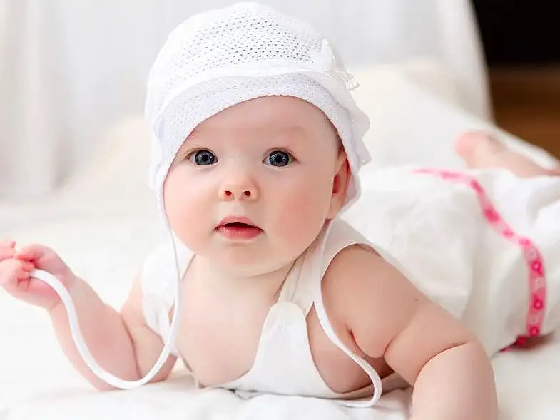Joue, Peau, Yeux, Blanc, Comfort, Textile, Baby, Baby & Toddler Clothing, Sourire, Rose, Headgear, Bambin, Happy, Cap, Enfant, Human Leg, Fashion Accessory, Linens, Room, Flash Photography, Personne, Headwear