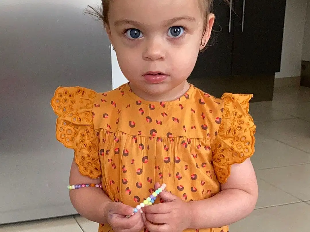 Peau, Facial Expression, Eyelash, Neck, Sleeve, One-piece Garment, Dress, Yellow, Day Dress, Waist, Baby & Toddler Clothing, Fashion Design, Trunk, Jewellery, Bambin, Formal Wear, Necklace, Pattern, Enfant, Embellishment, Personne
