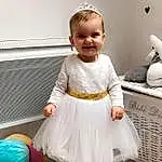 Sourire, Blanc, Dress, Baby & Toddler Clothing, Happy, Sleeve, Flash Photography, Bambin, Baby, Enfant, Event, Room, Assis, Day Dress, Fashion Design, Fashion Accessory, Pattern, Peach, Couch, Sock, Personne, Joy