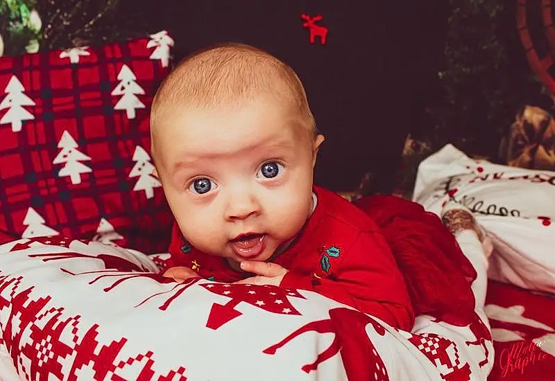 Head, Yeux, Sleeve, Baby, Baby & Toddler Clothing, Red, Happy, Bambin, Event, Holiday, Fun, Enfant, Assis, Linens, NoÃ«l, Carmine, Christmas Eve, Portrait Photography, Baby Products, Couch, Personne