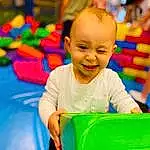 Sourire, Happy, Baby Playing With Toys, Bambin, Leisure, Fun, Baby, Recreation, Enfant, Kindergarten, Event, City, T-shirt, Assis, Baby & Toddler Clothing, Aire de jeux, Room, Play, Baby Products, Personne