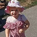Clothing, Peau, Sourire, Chapi Chapo, One-piece Garment, Sun Hat, Sleeve, Dress, Baby & Toddler Clothing, Happy, Cap, Gesture, Rose, People In Nature, Headgear, Cool, Bambin, Day Dress, Baseball Cap, Waist, Personne, Joy, Headwear