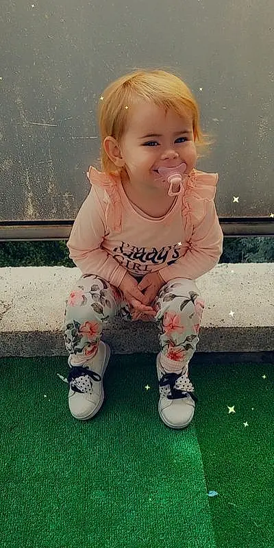 Hair, Joue, Peau, Head, Shoe, Coiffure, Sourire, Facial Expression, Baby & Toddler Clothing, Sleeve, Happy, Rose, Bambin, Baby, Herbe, Enfant, Blond, Pattern, Knee, Assis, Personne, Joy