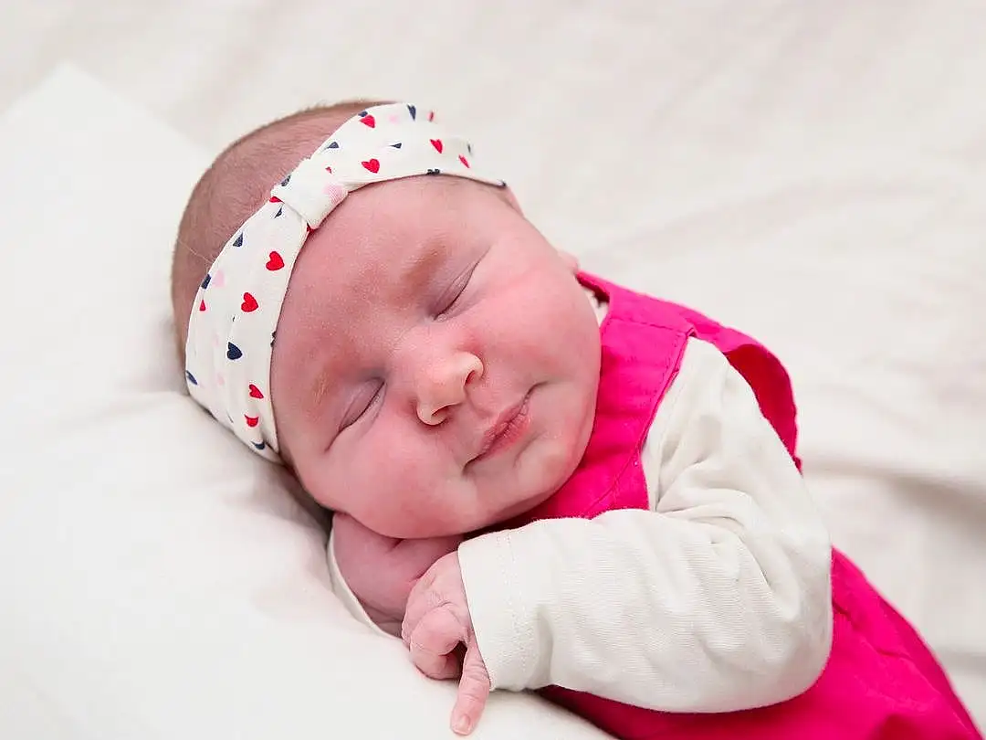 Joue, Head, Yeux, Comfort, Baby & Toddler Clothing, Sleeve, Baby, Headgear, Rose, Cap, Bambin, Happy, Baby Sleeping, Herbe, Fashion Accessory, Pattern, Magenta, Beanie, Enfant, Portrait Photography, Personne, Headwear