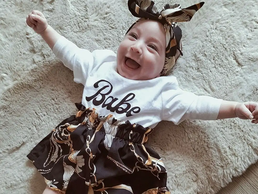 Visage, Head, Sourire, Yeux, Baby & Toddler Clothing, Human Body, Sleeve, Gesture, Happy, Finger, Bambin, Baby, Thigh, Bois, Thumb, Barefoot, Human Leg, T-shirt, Enfant, Foot, Personne, Headwear