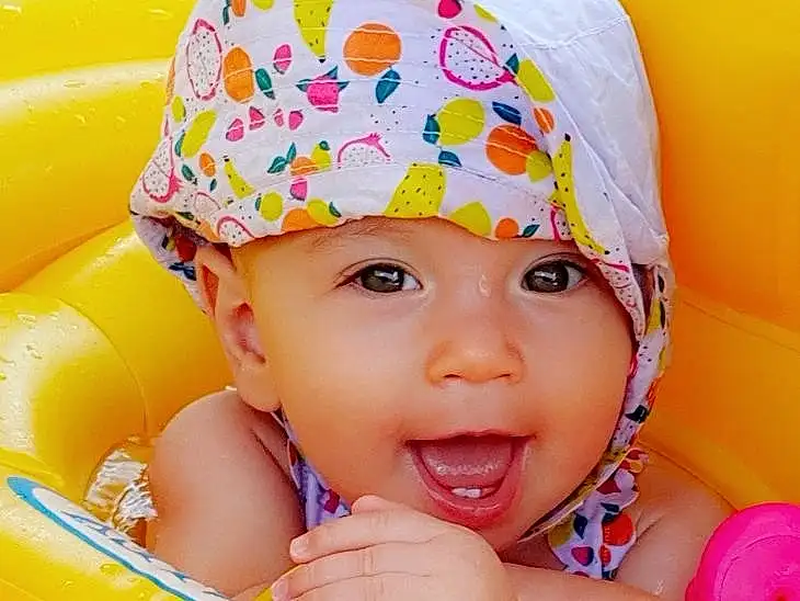Peau, Sourire, Photograph, Eau, Facial Expression, Cap, Happy, Baby Playing With Toys, Yellow, Baby, Rose, Fun, Leisure, Bambin, Playing With Kids, Aqua, Summer, Enfant, Recreation, Personne, Headwear