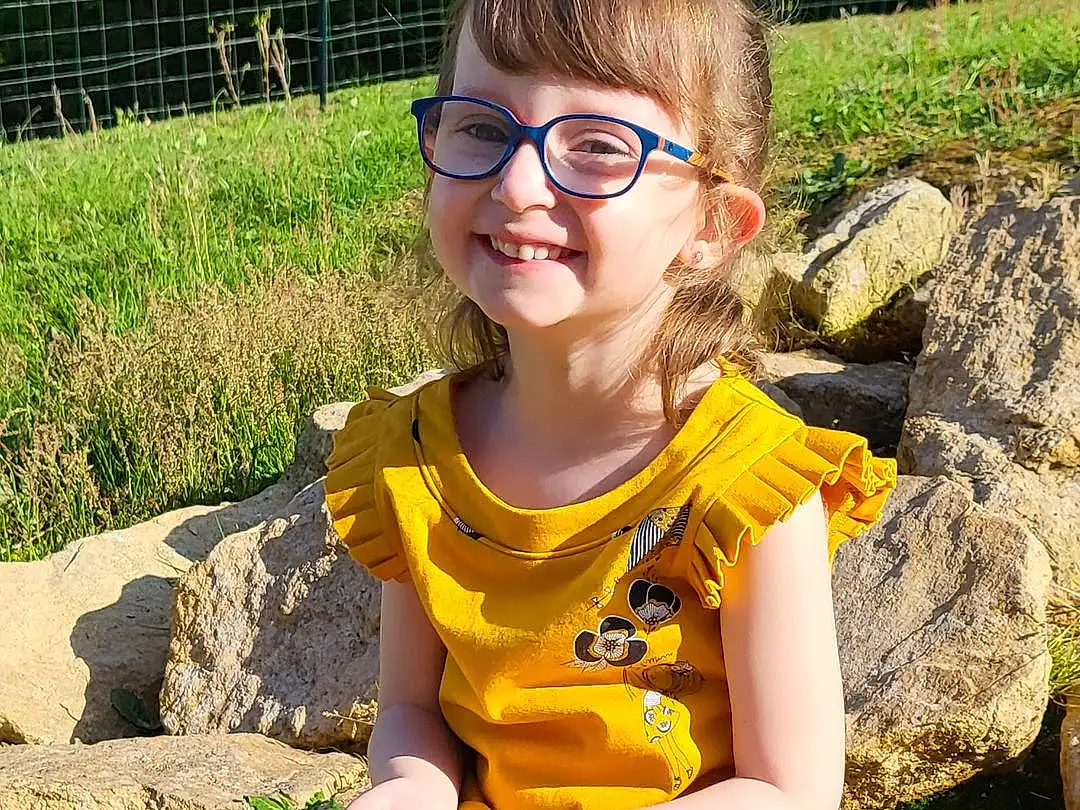 Visage, Lunettes, Sourire, Plante, Coiffure, Yeux, People In Nature, Yellow, Finger, Happy, Herbe, Thigh, Leisure, Fun, Bambin, Fence, Eyewear, Human Leg, Enfant, Blond, Personne, Joy