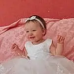 Clothing, Visage, Peau, Head, Coiffure, Sourire, Facial Expression, Dress, Bridal Clothing, Embellishment, Baby & Toddler Clothing, Sleeve, Textile, Happy, Flash Photography, Rose, Petal, Headgear, Gown, Baby, Personne, Joy